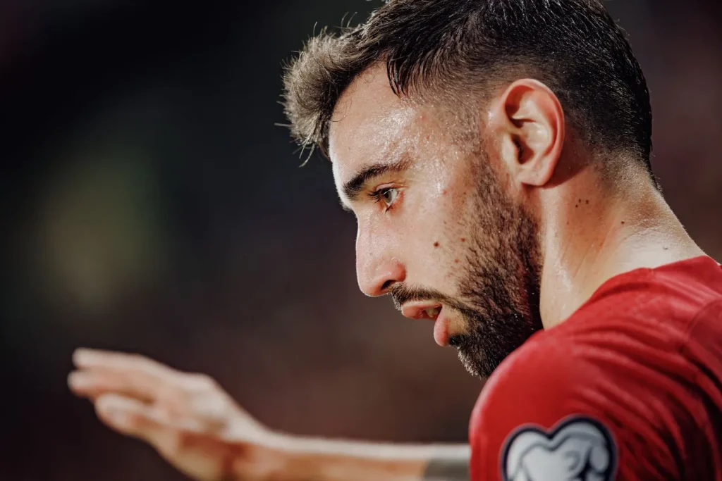 Bruno Fernandes im Fußballtrikot blickt nachdenklich nach links und hebt die rechte Hand