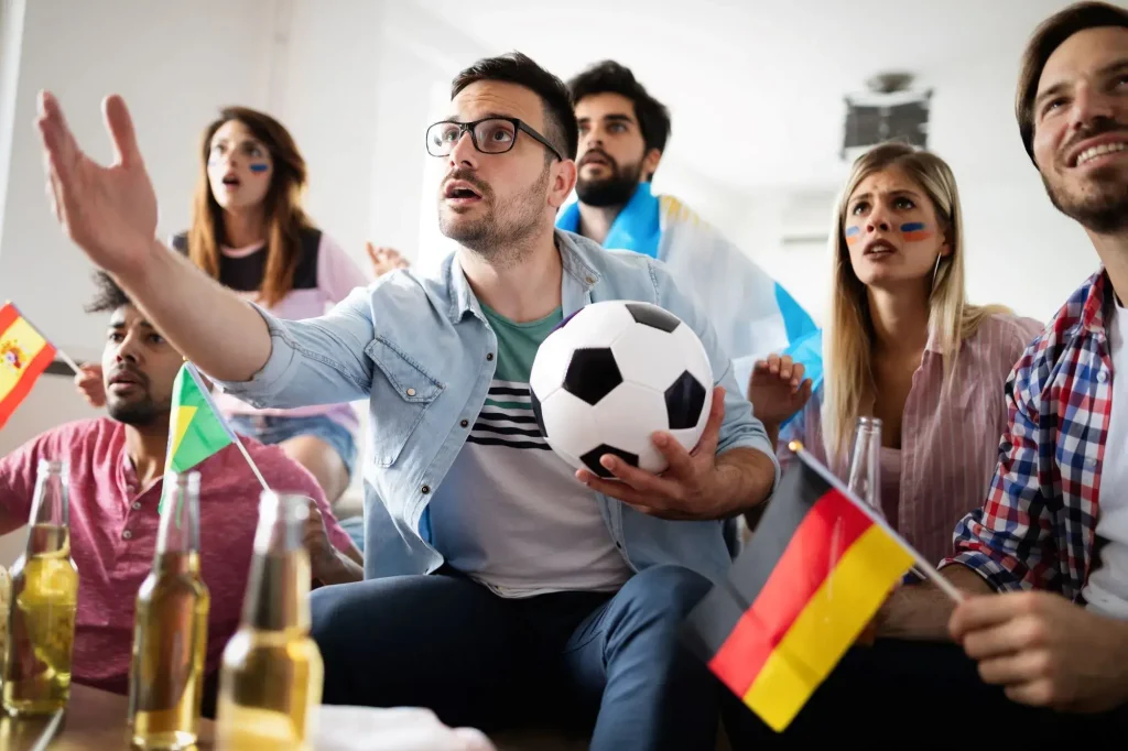Gruppe junger Personen guckt Fußball im Fernsehen und fiebert mit