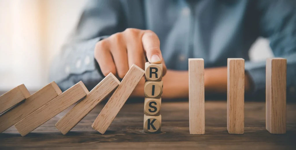 Mann kippt Spielsteine mit dem Schriftzug "Risiko" um