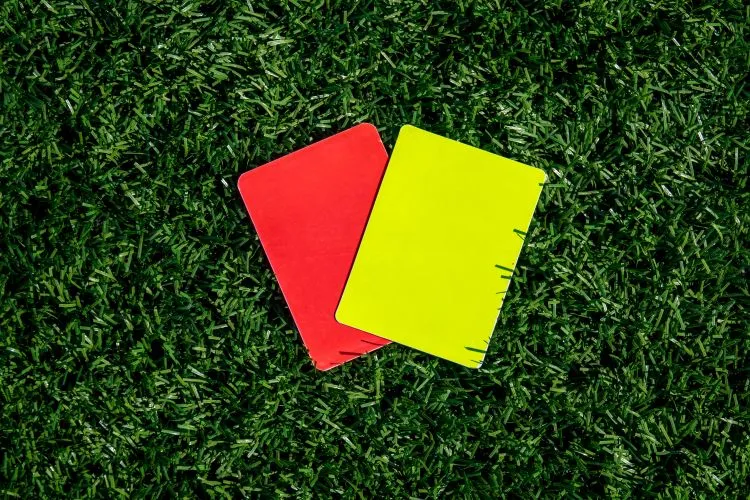 jeweils eine Gelbe Karte und eine Rote Karte liegen als Symbol für Rote und Gelbe Karten Wetten auf dem Fußballrasen