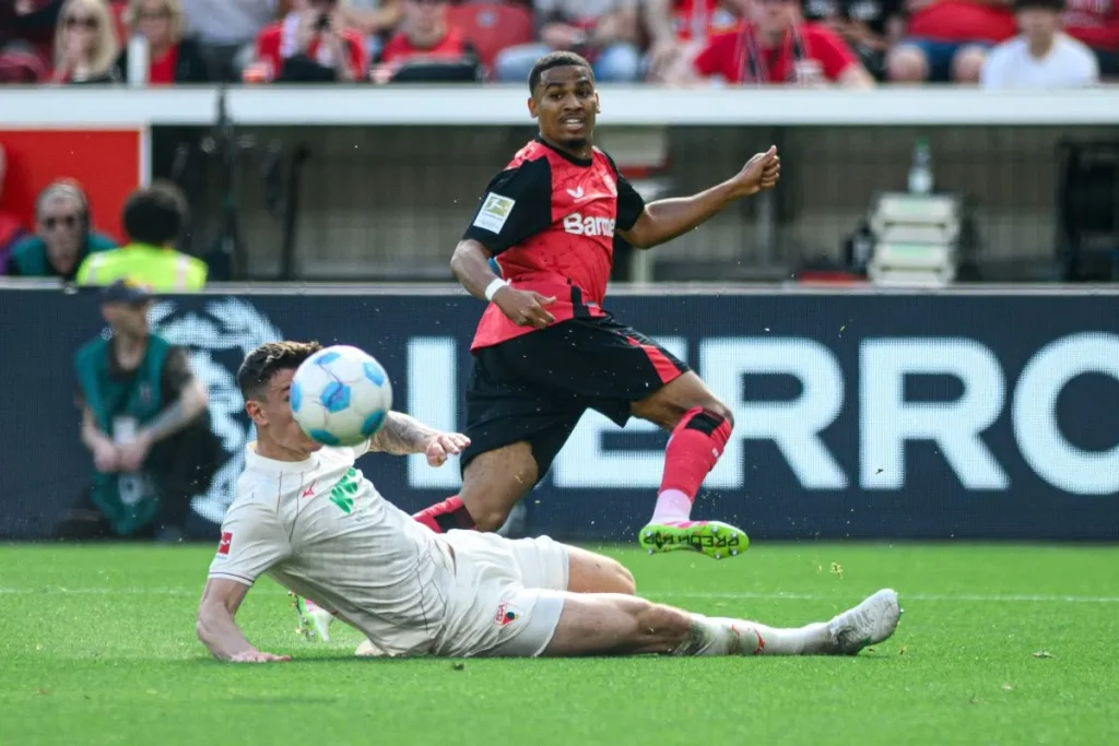 Spieler des FC Augsburg grätscht hart gegen einen Spieler von Bayer 04 Leverkusen