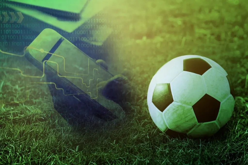 Fußball und im Hintergrund ein aufs Smartphone tippender Mann